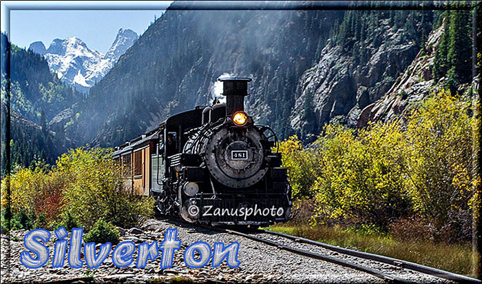 Silverton, andampfender Train mit Schneebergen im Hintergund fährt über die Animas River Bridge