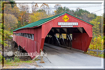 New England - Vermont, eine Covered Bridge mit roten Seitenwänden sehen wir vor uns an der Fahrbahn