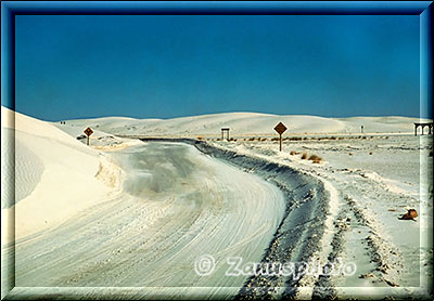 Fahrbahn teils mit weissem Sand zugeweht