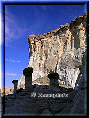 Kleine Hoodoos im Schatten vor sonnenbeschienener Felswand